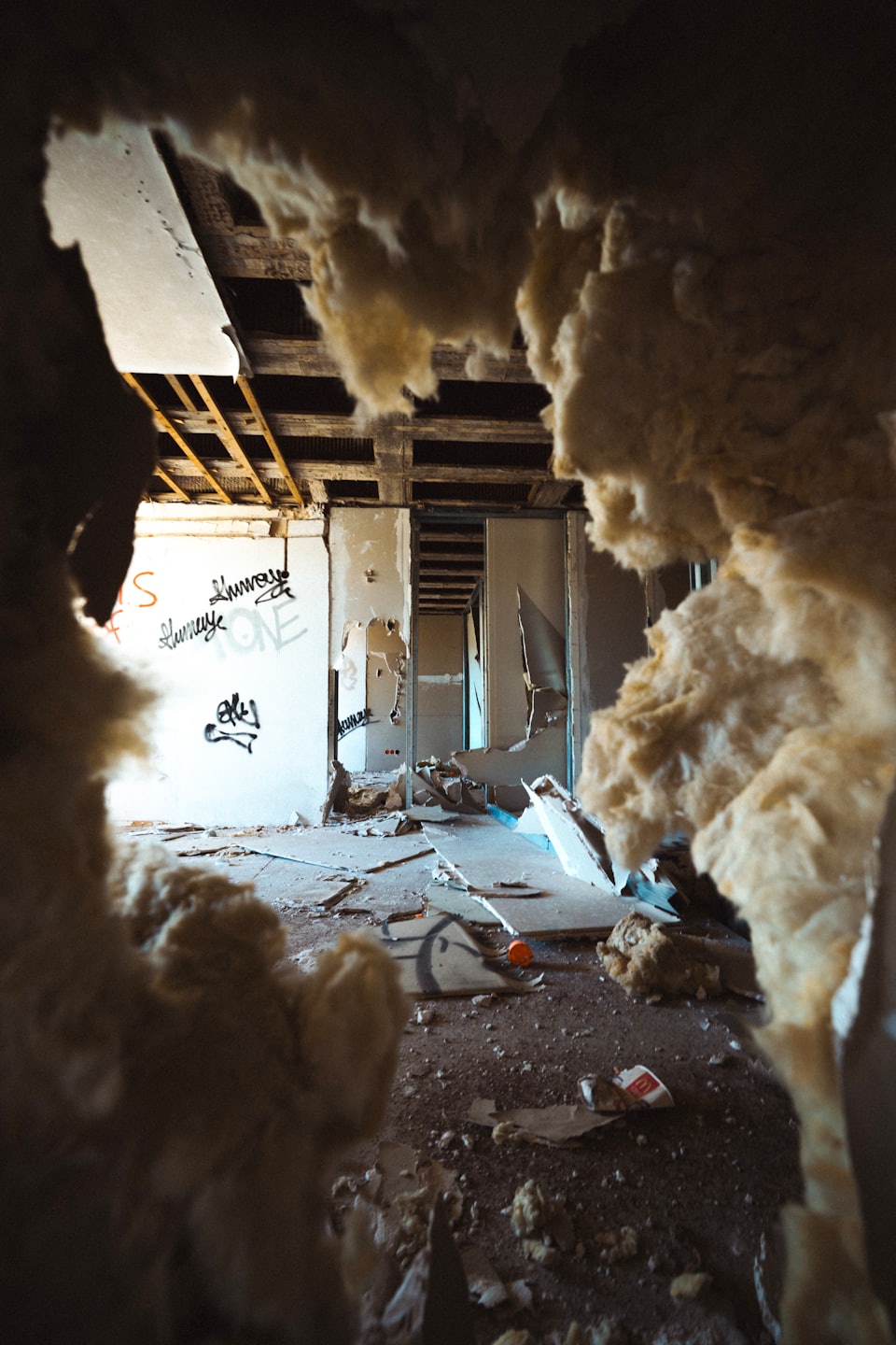 Damaged room with exposed wooden joists and crumbling drywall.